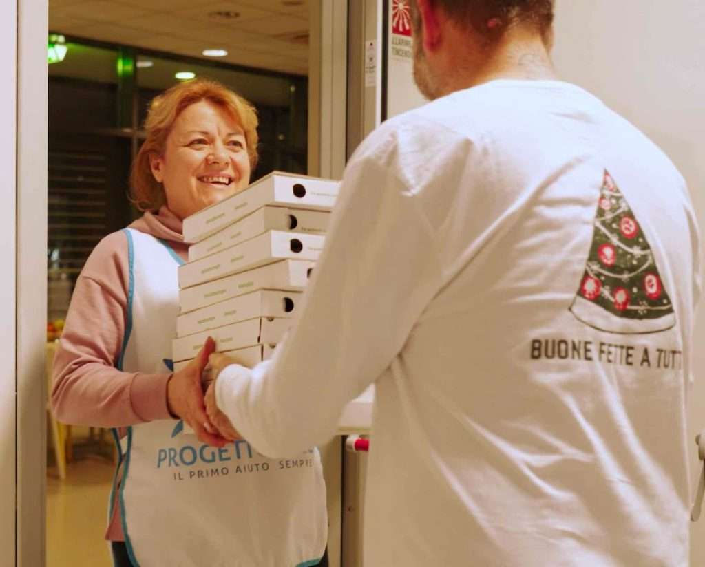 nella foto: Denis Milano consegna le pizze ai volontari di Progetto Arca. fonte Aromi Group