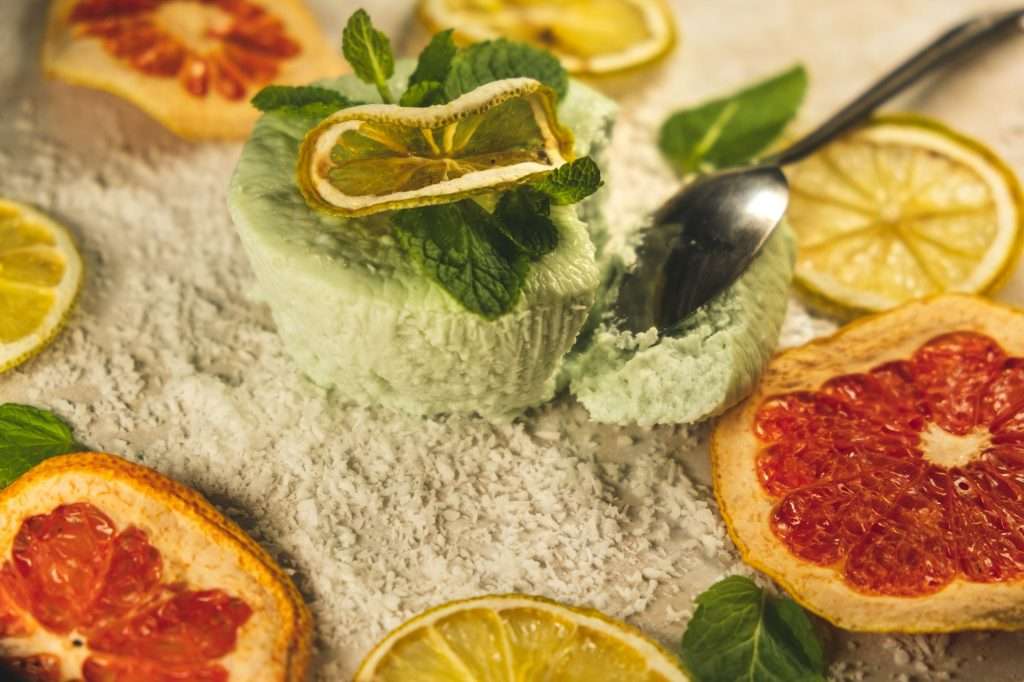 Selective focus shot of a dessert with mint and lemon, grapefruits, lemons, and mint on the table