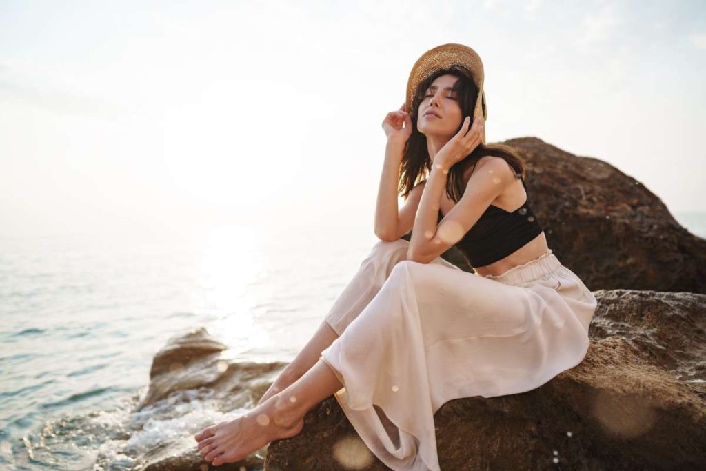 Woman traveler sitting near sea on cliff injoying view of sea and nature