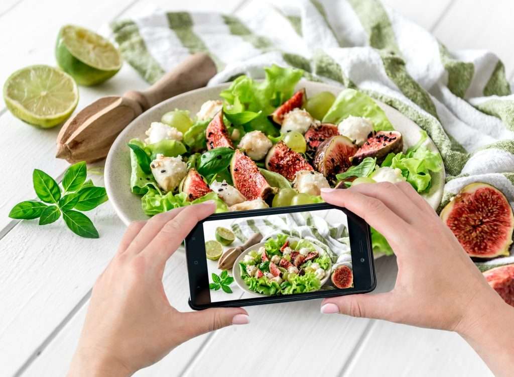 Women's hands photograph vegetarian salad