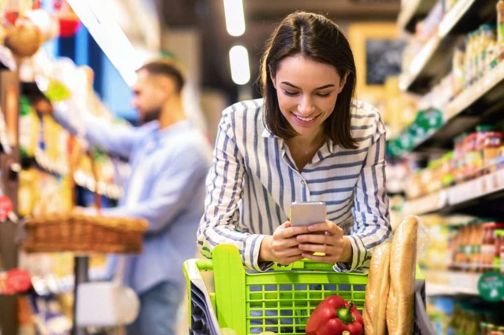 Young lady with mobile phone shopping at super market